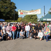 people pose in front of a farmers market banner and USDA farmers market tent