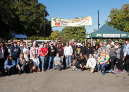 people pose in front of a farmers market banner and USDA farmers market tent